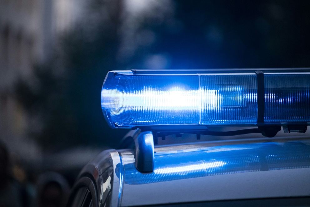 Policijas auto ar ieslēgtām zilām bākugunīm nakts tumsā.