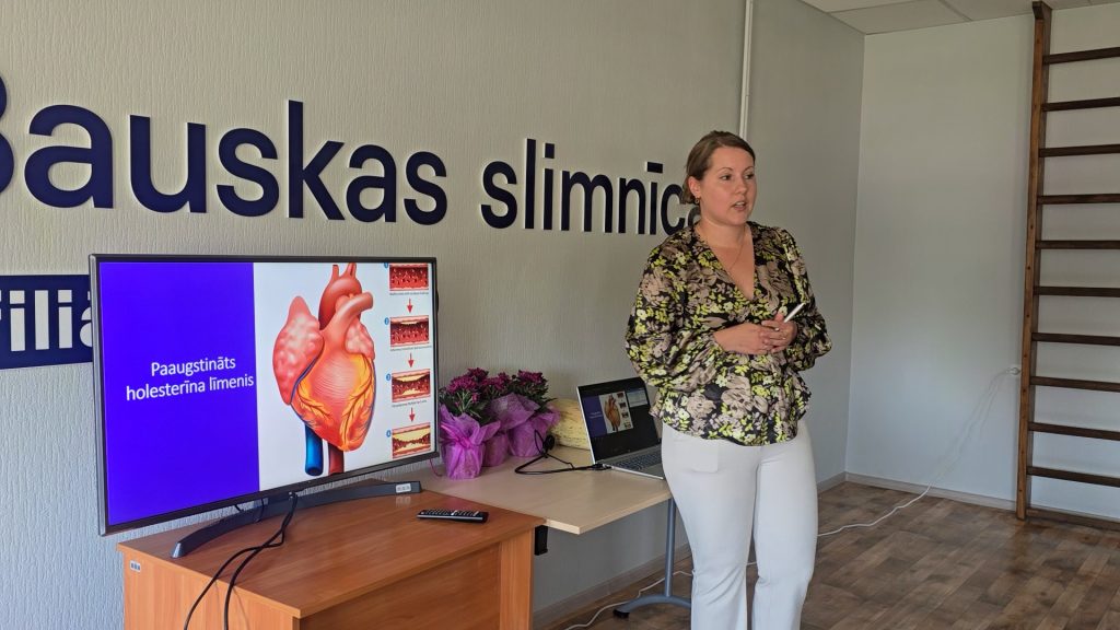 Sieviete stāv pie televizora, runājot lekcijas laikā
