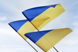 Ukrainas karogi plīvo vējā uz debesu fona