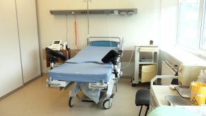 Slimnīcas palāta ar dzemdību gultu un medicīnas aprīkojumu