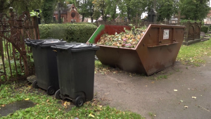 Atkritumu konteineri kapsētā pie kapu vārtiem
