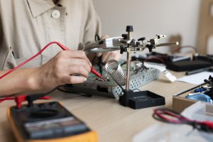 Jauns izgudrotājs pārbauda elektronisko shēmu ar mērinstrumentiem laboratorijā.