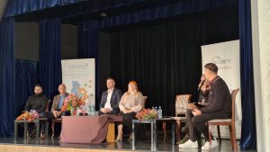 Diskusijas dalībnieki sēž uz skatuves, runājot par uzņēmējdarbību un sadarbību Jelgavas novadā.