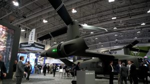 Izstādes apmeklētāji aplūko militāro helikopteru un jaunākās tehnoloģijas aizsardzības industrijas pasākumā.
