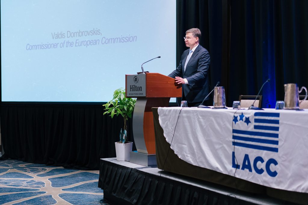 Eiropas Komisijas komisārs Valdis Dombrovskis uzstājas pie tribīnes konferencē “Spotlight Latvia”. Aiz viņa redzams ekrāns ar viņa vārdu un amatu.