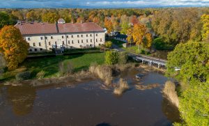 Panorāmas skats no putna lidojuma uz Dundagas pili, dīķi, rudens kokiem un tīrīšanas amfībiju.