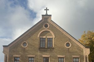 Ventspils baptistu baznīcas fasāde no priekšpuses, ar jaunu, uzstādītu krustu jumta kores augšgalā.