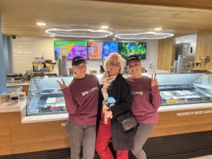 Divas “Ben & Jerry’s” darbinieces un žurnāliste smaida pie saldējuma letes jaunajā veikalā.