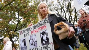 Sieviete ar suni piedalās protesta akcijā, turot plakātu ar uzrakstu “Trīs dzīvības – nevainīgas, bet atņemtas. Taisnīgums?”.