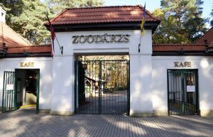 Galvenā ieeja Rīgas Zooloģiskajā dārzā ar uzrakstu "ZOODĀRZS", divām kasēm un Latvija un Ukrainas karogiem.