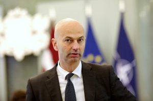 Jānis Citskovskis, fonā redzami Latvijas un NATO karogi.