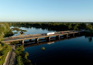 Kravas automašīna un automašīnas uz jaunā tilta pār Salacas upi Salacgrīvā, skats no augšas.