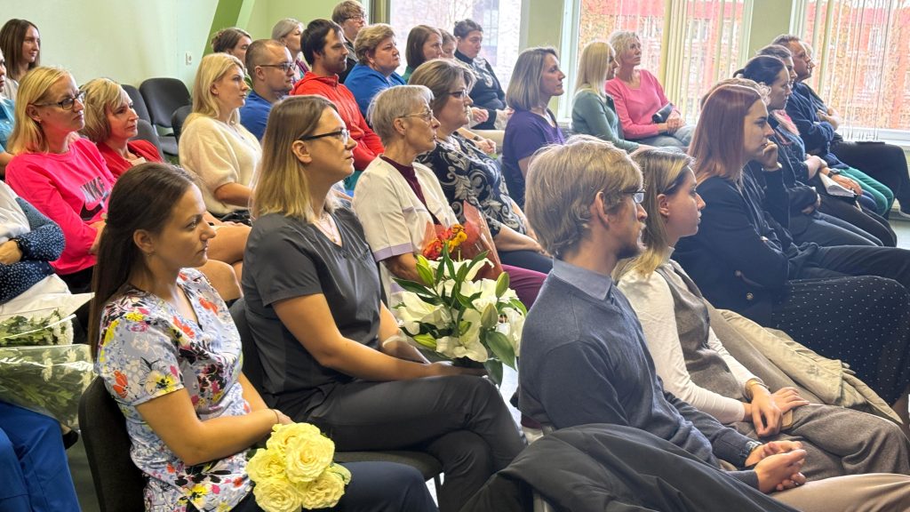 Jēkabpils reģionālās slimnīcas personāls sēž rindās zālē, klausoties uzrunu pasākumā, kas veltīts jauno speciālistu uzņemšanai.