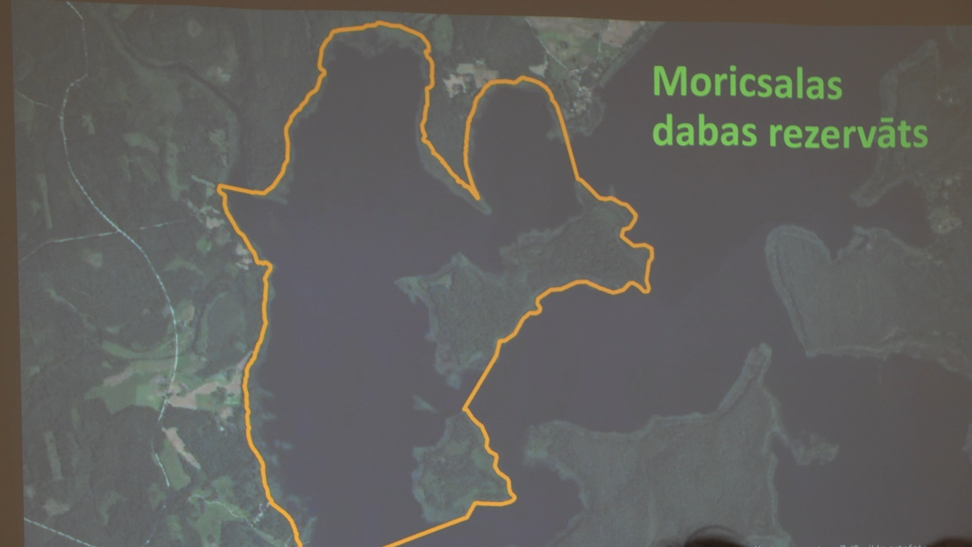 Moricsalas dabas rezervāta robežu digitāls attēlojums uz satelītkartes projekcijas ekrānā publiska pasākuma laikā.