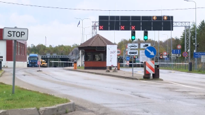 Autoceļu robežkontroles punkts ar ceļazīmēm, STOP zīmi un zaļo luksofora signālu, kas ļauj transportam šķērsot robežu.