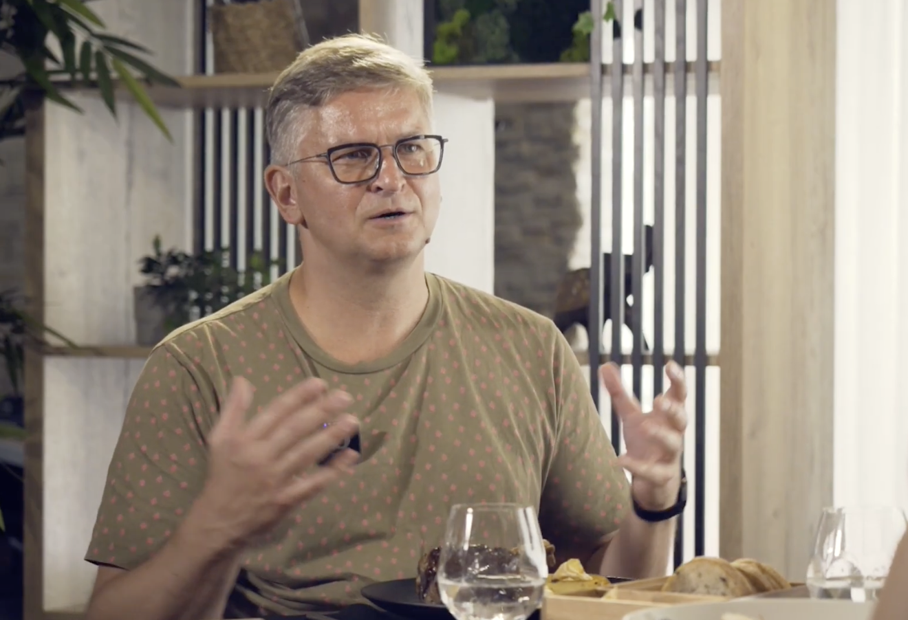 Ints Teterovskis sarunas laikā sēž pie galda ar ēdienu un žestikulē, izsakot domu.