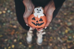 Rokas tur Helovīna tēmu cepumu – ķirbi ar izgrieztu seju un mazu spoku.