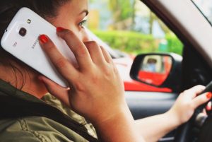 Sieviete runā pa telefonu, vadot automašīnu – uzmanības novēršana pie stūres.