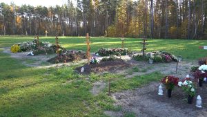 Jaunu kapavietu laukums Jelgavas Meža kapsētā ar koka krustiem un ziediem.