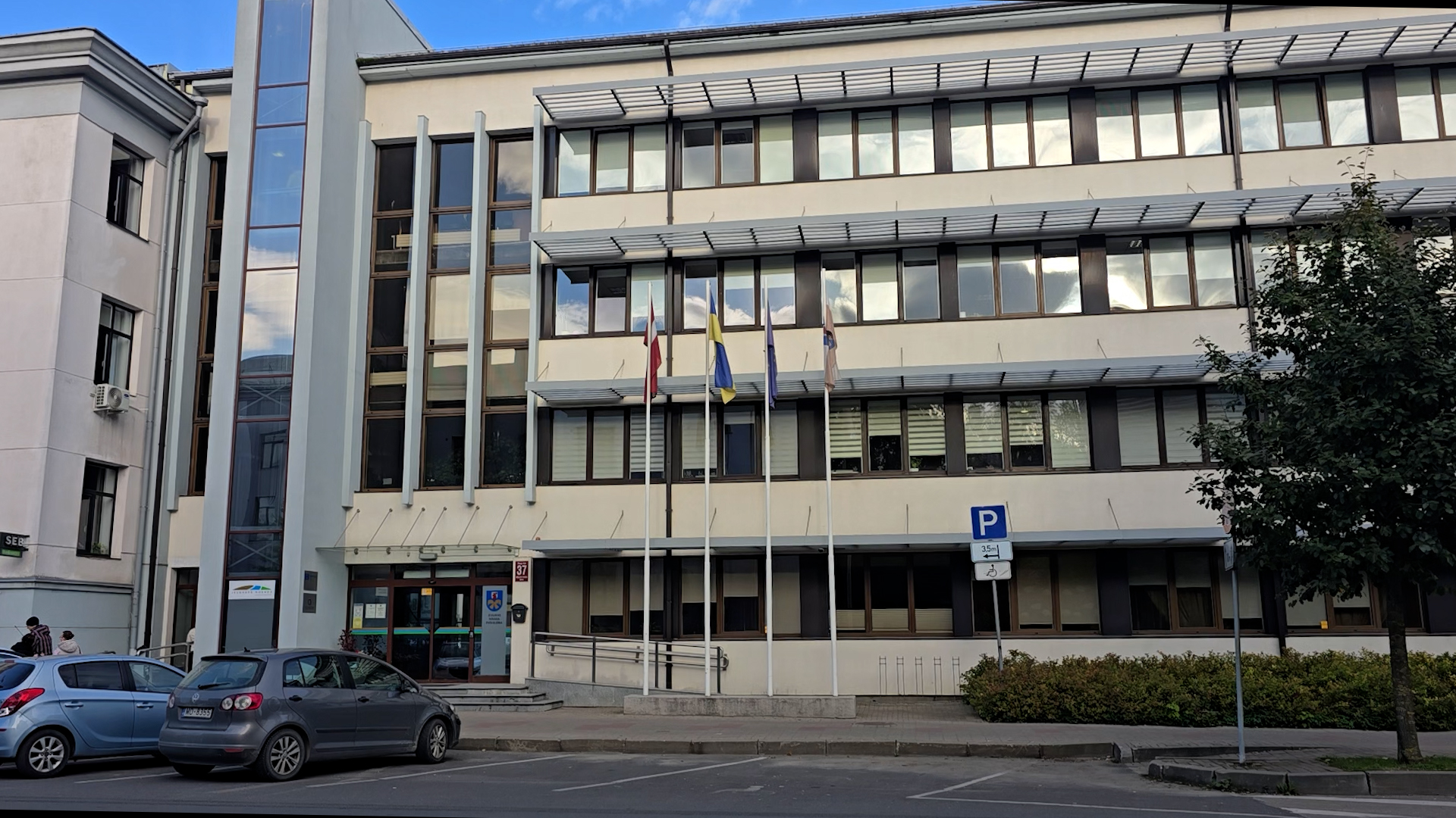 Jelgavas novada pašvaldības galvenā ieeja ar pašvaldības ģerboni uz stikla durvīm.
