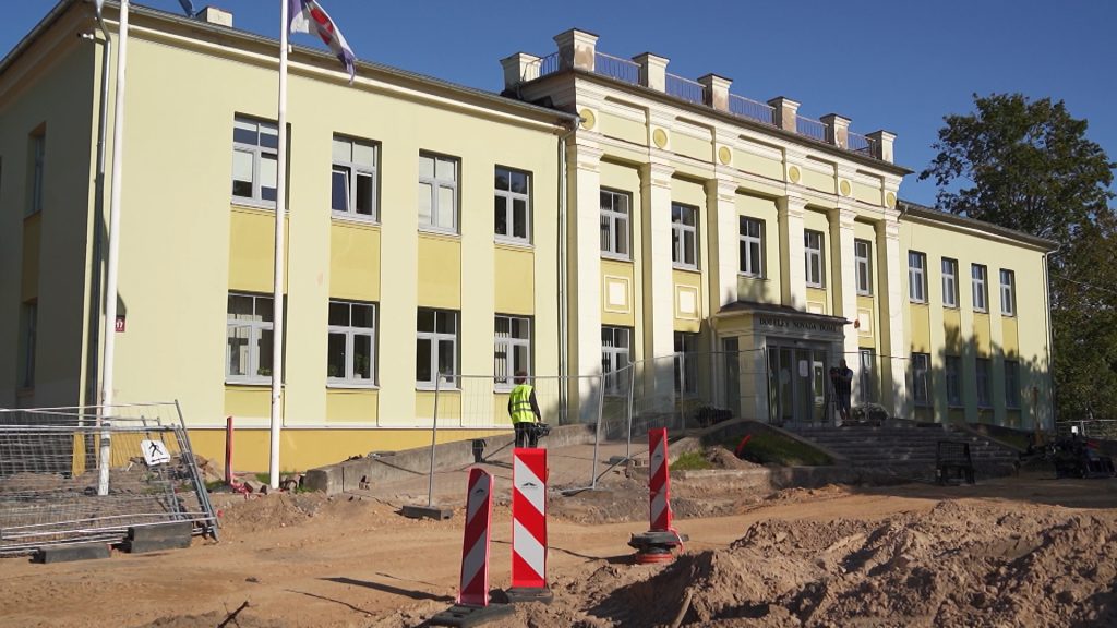 Vecs, gaiši dzeltens divstāvu nams ar kolonnām priekšā - Dobeles novada pašvaldības ēka, kura priekšā notiek būvdarbi.