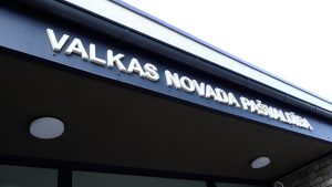 Valkas novada pašvaldības ēkas izkārtne ar uzrakstu uz ieejas nojumes.