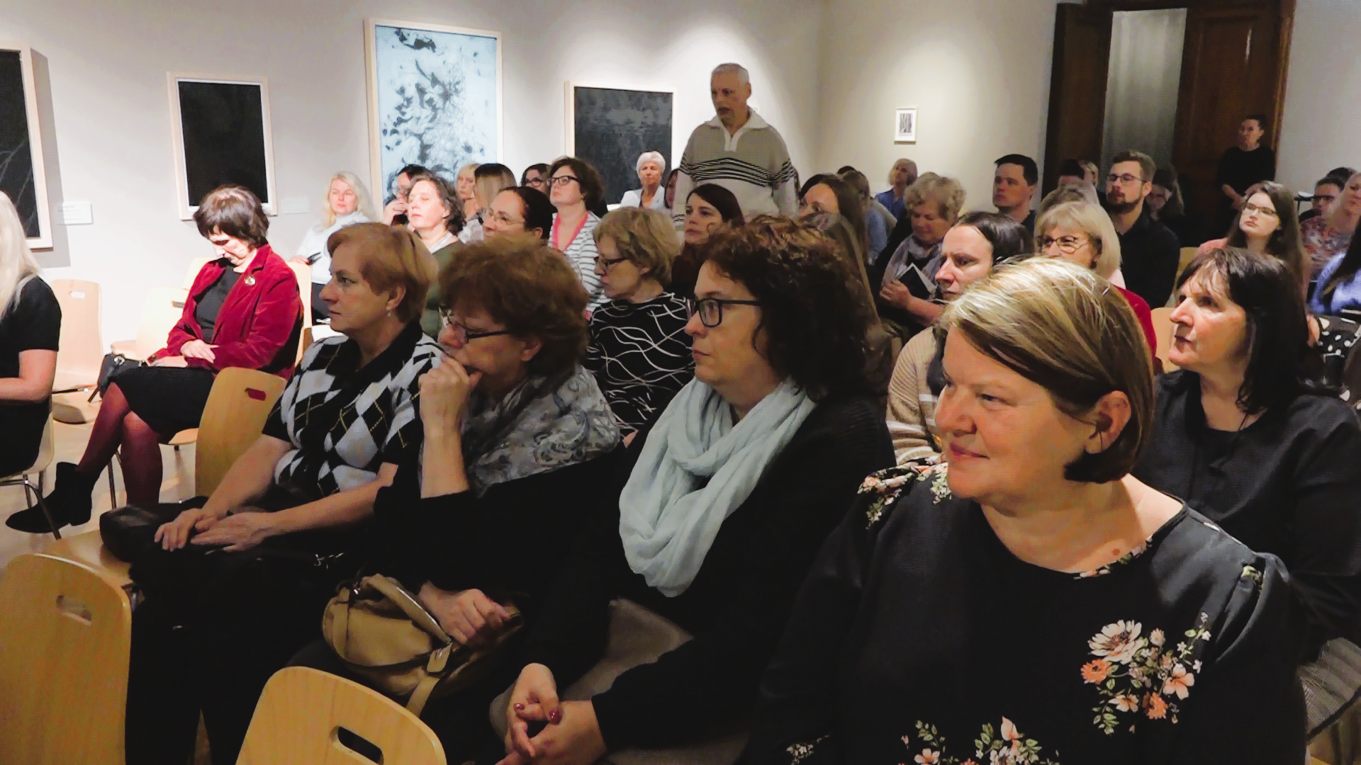 Digitālā mantojuma dienas dalībnieki – daudzskaitlīga auditorija, kas sēž koka krēslos un uzmanīgi klausās prezentācijā Liepājas muzejā.