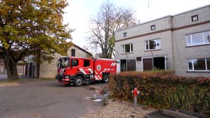 Ugunsdzēsēju automašīna pie glābšanas depo ēkas rudenīgā dienā.