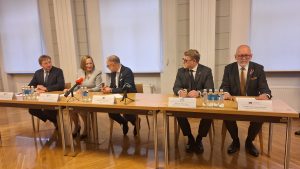 Aizsardzības ministrs un četru Latvijas universitāšu rektori sēž pie galda preses konferences laikā.