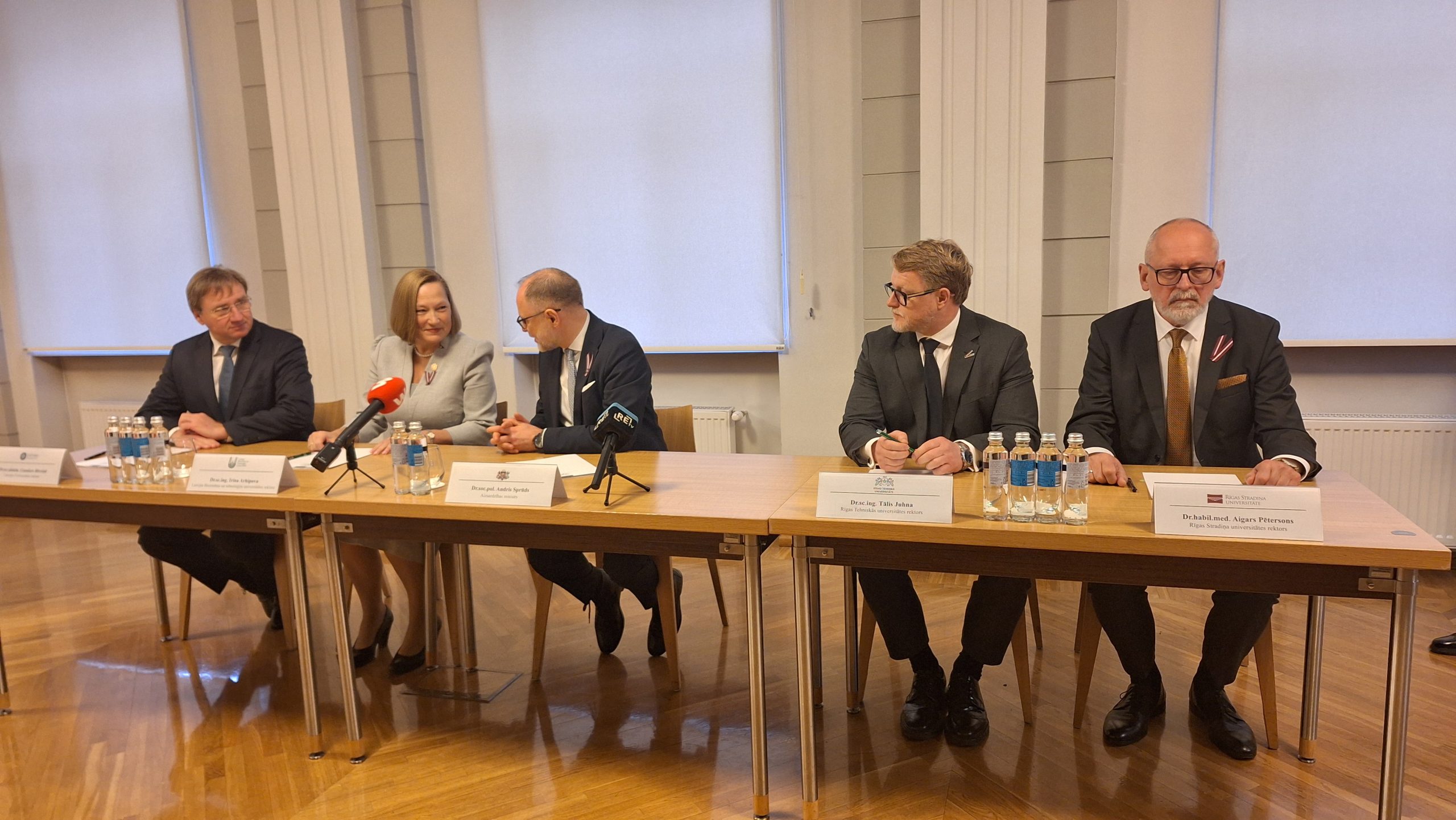 Aizsardzības ministrs un četru Latvijas universitāšu rektori sēž pie galda preses konferences laikā.