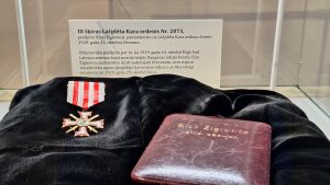 Elzas Žiglevicas Lāčplēša Kara ordeņa Nr. 2073 ekspozīcija ar medaļu un dokumentu muzeja vitrīnā.