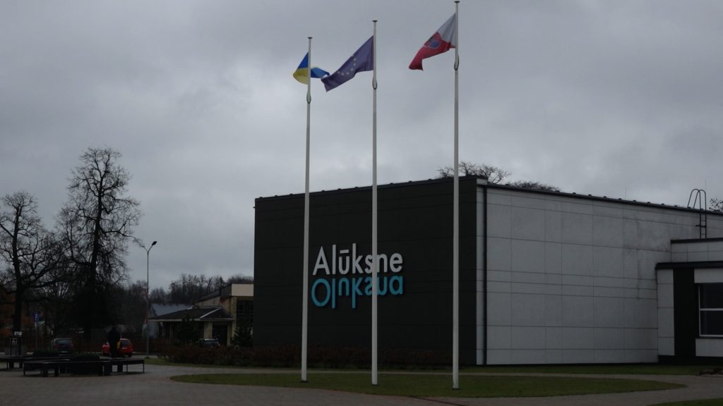 Ēka ar uzrakstu "Alūksne" un mastos karājas Ukrainas, Eiropas Savienības un Latvijas karogi.