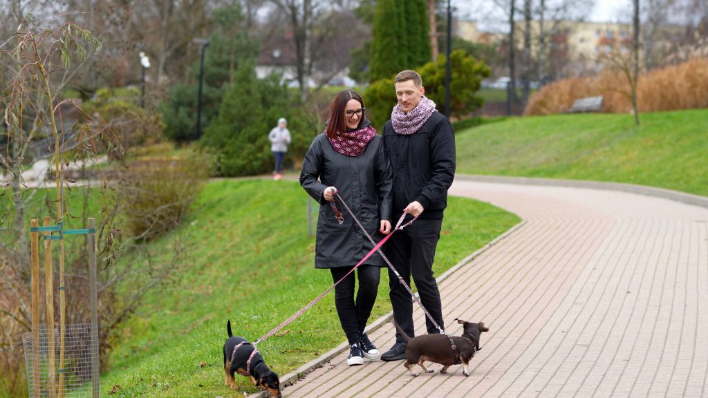 Kristiāna Ivanova un vīrs staigā pa parku ar diviem maziem takšu šķirnes suņiem pavadā
