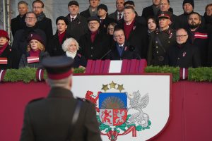 Cilvēki svinīgā pasākumā pie Latvijas ģerboņa tribīnes valsts svētku laikā.