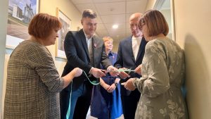Jēkabpils novada Pašvaldības pārstāvji svinīgi griež zilu lenti Ancenes bibliotēkas atklāšanas brīdī