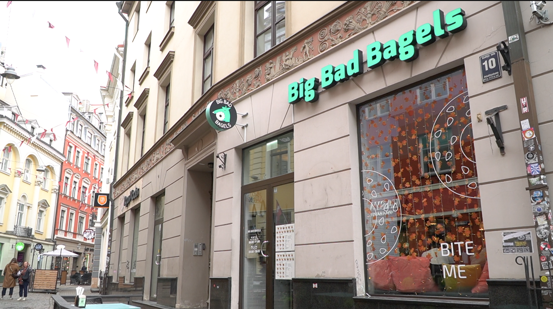 “Big Bad Bagels” kafejnīcas ēka Rīgas centrā ar gaišām fasādēm un izkārtni virs ieejas.