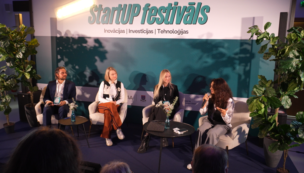 Četri cilvēki sēž uz skatuves, piedaloties paneļdiskusijā "StartUp" festivālā