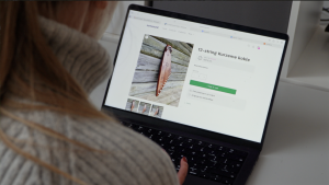 Persona datorā aplūko 12-stīgu Kurzemes kokles produktu lapu tiešsaistes veikalā