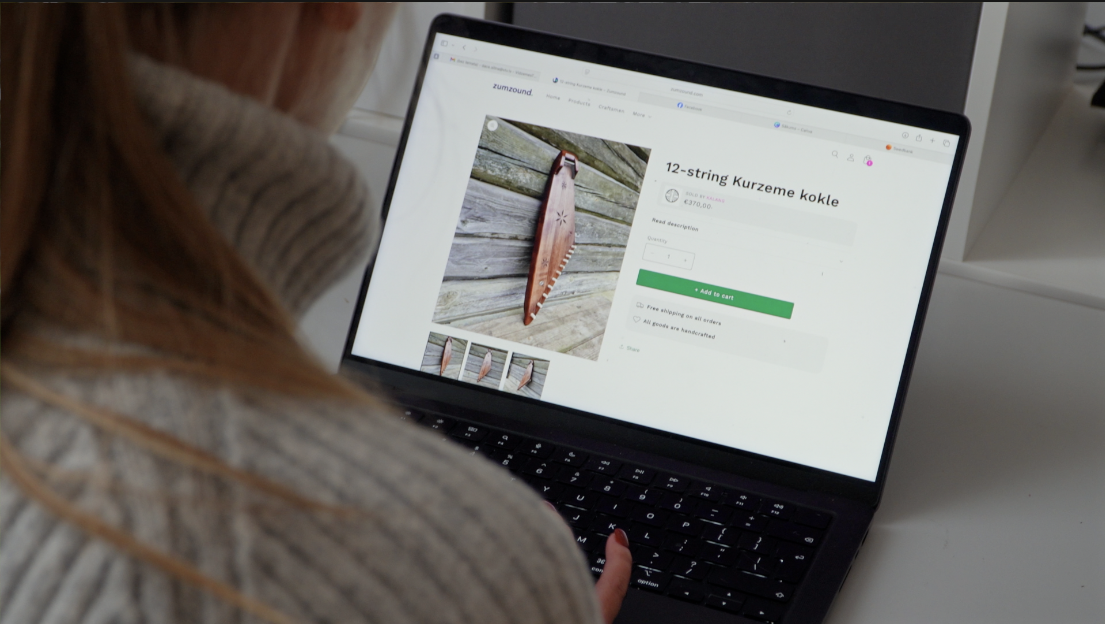 Persona datorā aplūko 12-stīgu Kurzemes kokles produktu lapu tiešsaistes veikalā