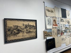 Cēsu Izstāžu nama ekspozīcijas siena ar vēsturiskām mākslas dienu afišām un mākslinieku skiču darbiem.
