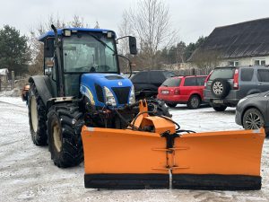Traktors ar sniega lāpstu stāvvietā ziemas apstākļos