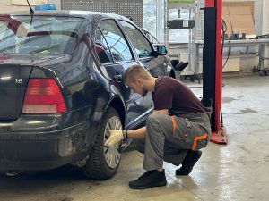 Topošais automehāniķis Aizkraukles Profesionālajā vidusskolā maina riepu automašīnai.