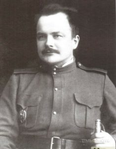 Jānis Lapiņš militārā uniformā, sēžot portretam.