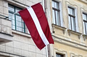 Latvijas valsts karogs pie ēkas fasādes svētku laikā.