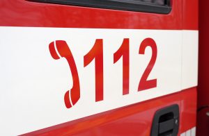 Glābšanas dienesta 112 tālruņa numura uzraksts uz sarkanbalta dienesta auto.
