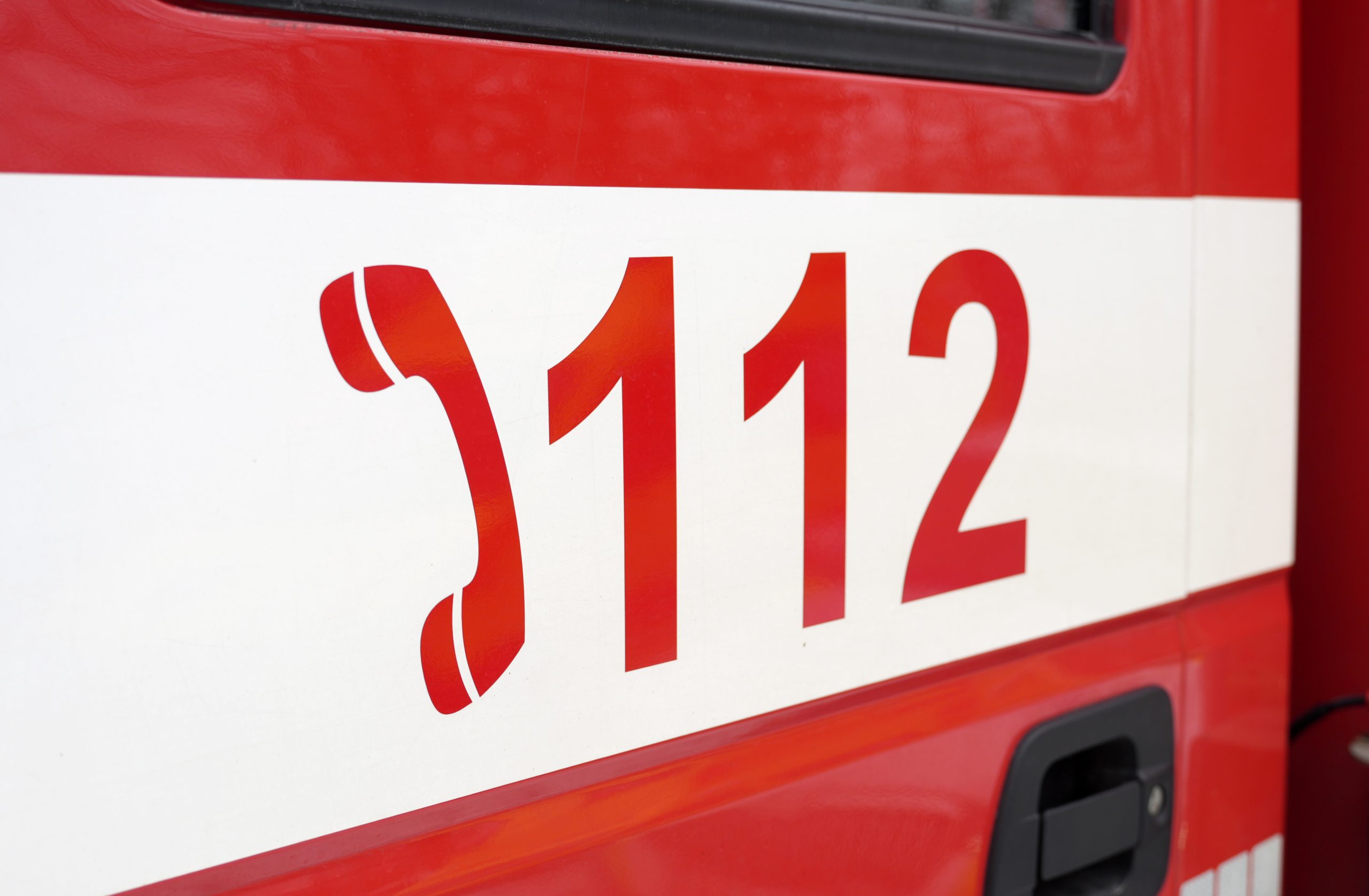 Glābšanas dienesta 112 tālruņa numura uzraksts uz sarkanbalta dienesta auto.