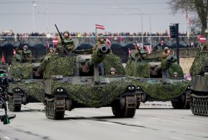 Pašgājējhaubices "M109" (vai līdzīga militārā tehnika) ar maskēšanās tīkliem militārās parādes laikā uz ielas.