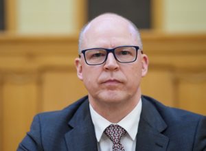 Armīns Meisters sēž iekštelpās oficiālā pasākumā.