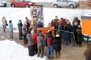 Iedzīvotāju pikets pie Siguldas domes ēkas ar barjerām un plakātu, ziemas apstākļos.