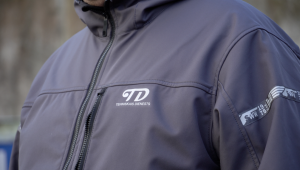 Darba jaka ar uzņēmuma “Tehniskais dienests” logotipu tuvplānā.
